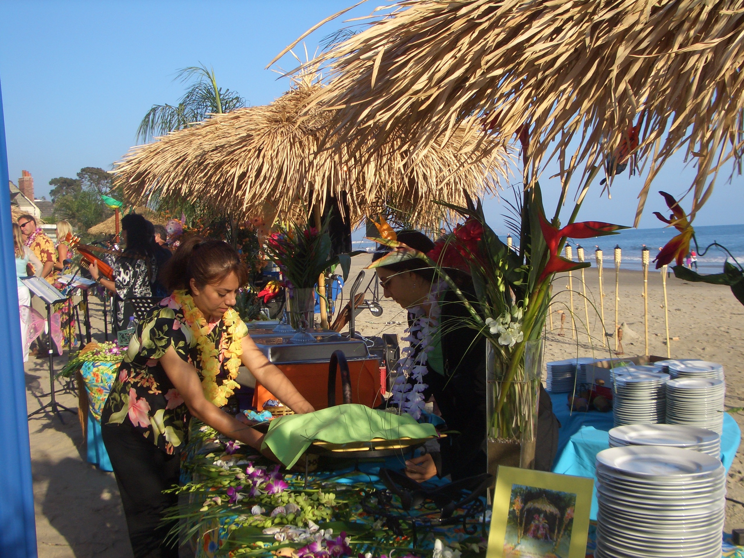 Tiki bar setup with bamboo bar and staff serving guests at corporate luau